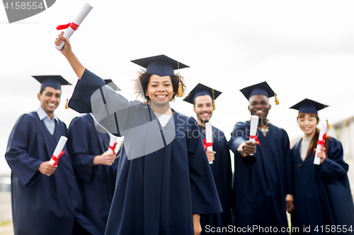 Image of happy students in mortar boards with diplomas