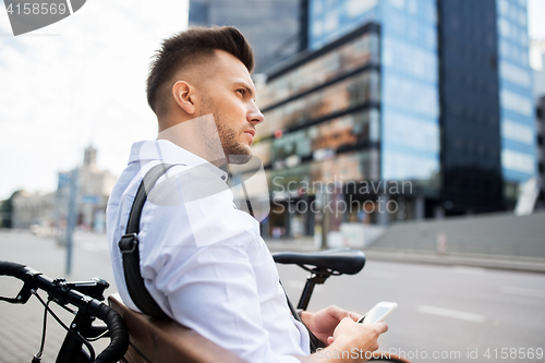 Image of man with smartphone and bicycle in city