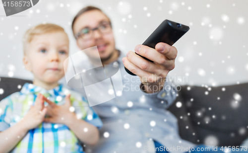 Image of father and son with remote watching tv at home