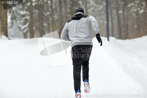 Image of man running on snow covered winter road in forest