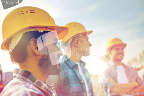 Image of group of smiling builders in hardhats outdoors