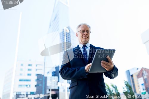 Image of senior businessman with tablet pc on city street