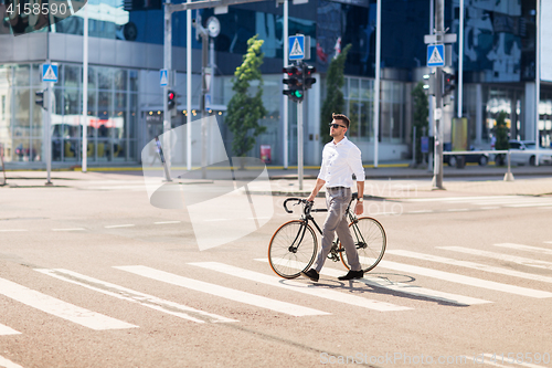 Image of young man with bicycle on crosswalk in city
