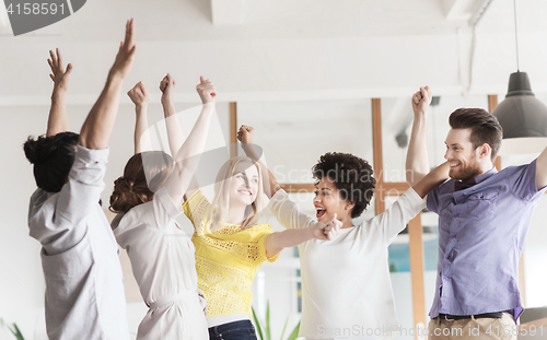 Image of happy creative team celebrating victory in office