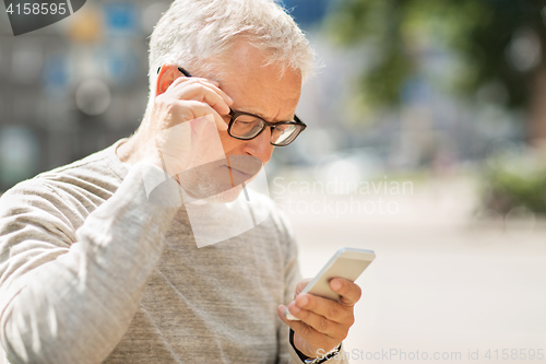 Image of senior man texting message on smartphone in city