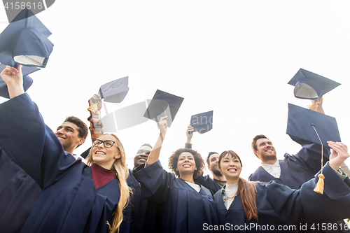 Image of happy students or bachelors waving mortar boards