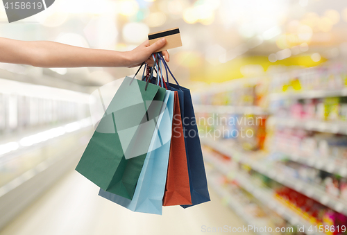 Image of hand with shopping bags and credit card at store