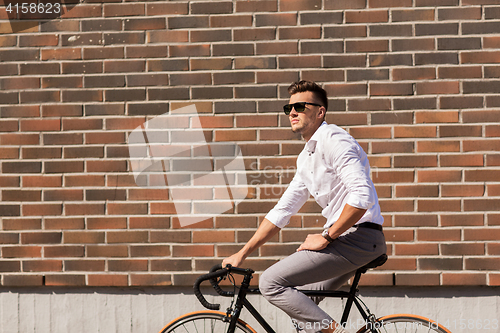 Image of young man riding bicycle on city street