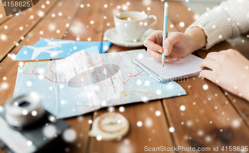Image of hands with map and coffee writing to notebook