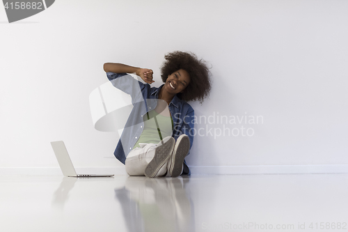 Image of african american woman sitting on floor with laptop