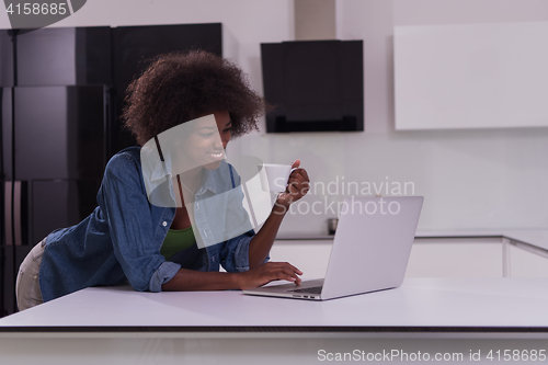 Image of smiling black woman in modern kitchen