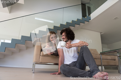 Image of couple relaxing at  home with tablet computers