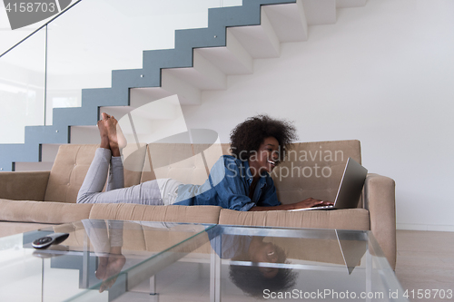 Image of African American woman using laptop on sofa