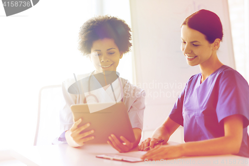 Image of happy doctors with tablet pc meeting at hospital