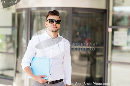 Image of young man with business file on city street