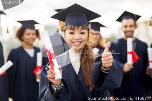 Image of happy students with diplomas showing thumbs up