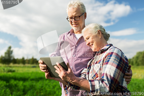 Image of happy senior couple with tablet pc at summer farm