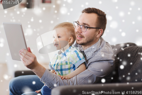 Image of father and son with tablet pc playing at home