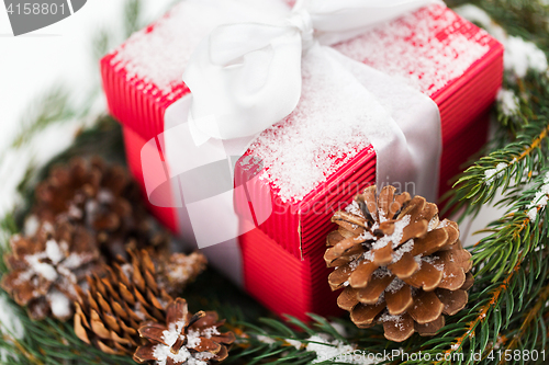 Image of close up of christmas gift and fir wreath on snow