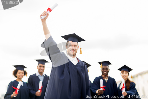 Image of happy students in mortar boards with diplomas