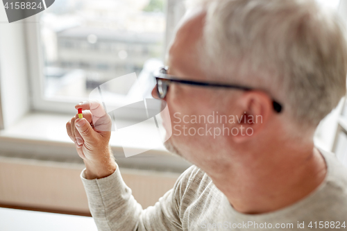 Image of close up of old man holding pill