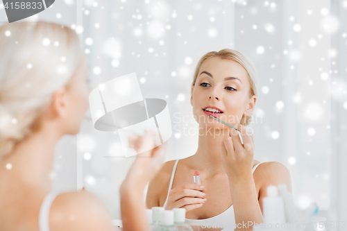 Image of woman with lipstick applying make up at bathroom