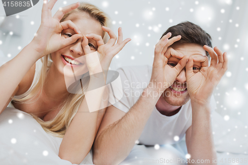 Image of happy couple lying in bed at home