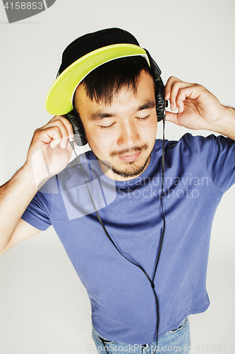 Image of young asian man in hat and headphones listening music on white b