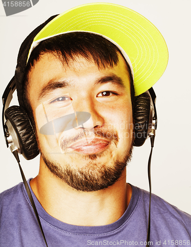 Image of young asian man in hat and headphones listening music on white b