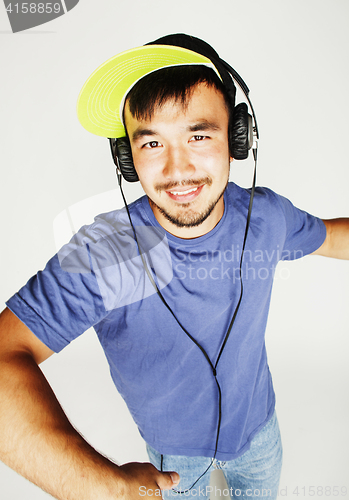 Image of young asian man in hat and headphones listening music on white b