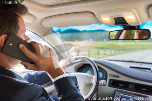 Image of Man using cell phone while driving
