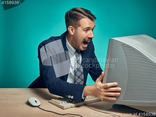 Image of Portrait of cheerful young businessman sitting with computer