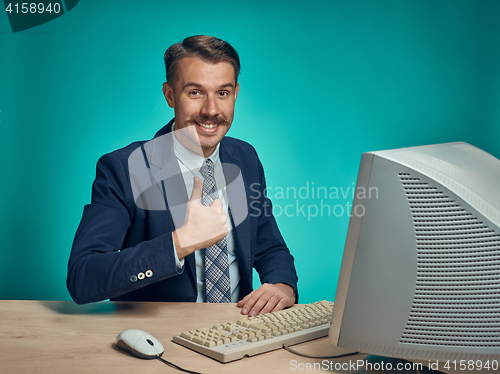 Image of Portrait of cheerful young businessman sitting with computer