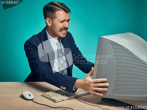 Image of Angry businessman using a monitor against blue background