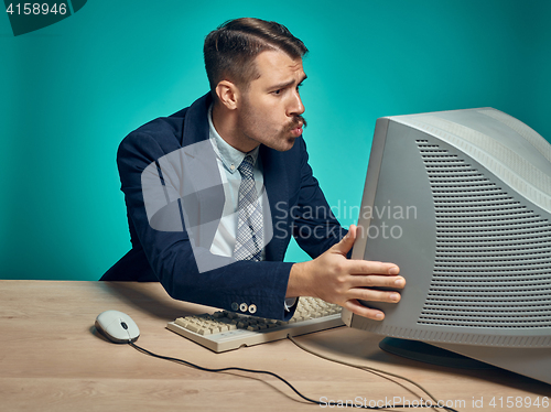 Image of Portrait of cheerful young businessman sitting with computer