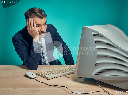 Image of Sad Young Man Working On computer At Desk