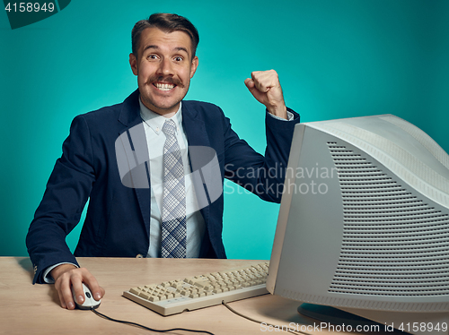 Image of Portrait of cheerful young businessman sitting with computer