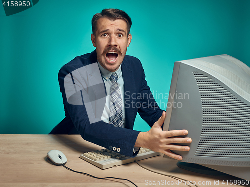 Image of Angry businessman using a monitor against blue background