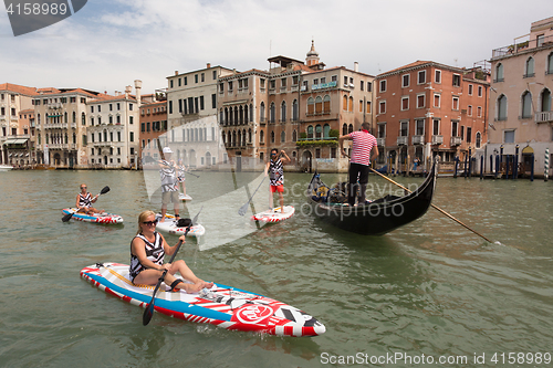 Image of Group of active tourists stand up paddling on sup boards at Grand Canal, Venice, Italy.