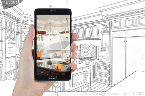 Image of Hand Holding Smart Phone Displaying Photo of Kitchen Drawing Beh