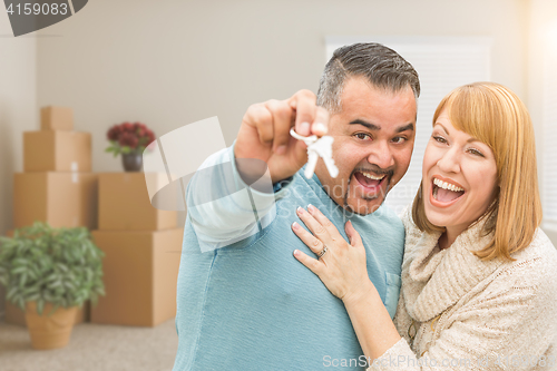 Image of Couple Holding House Keys Inside Empty Room with Moving Boxes