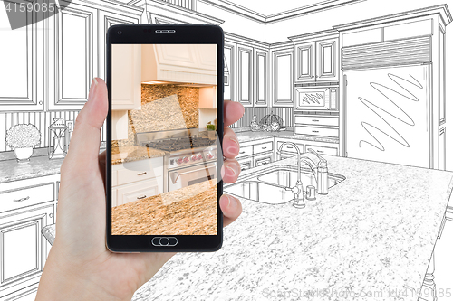 Image of Hand Holding Smart Phone Displaying Photo of Kitchen Drawing Beh