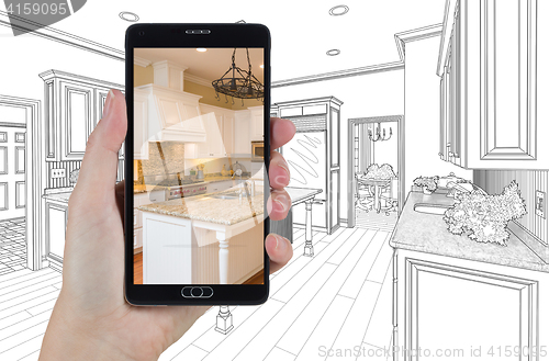 Image of Hand Holding Smart Phone Displaying Photo of Kitchen Drawing Beh