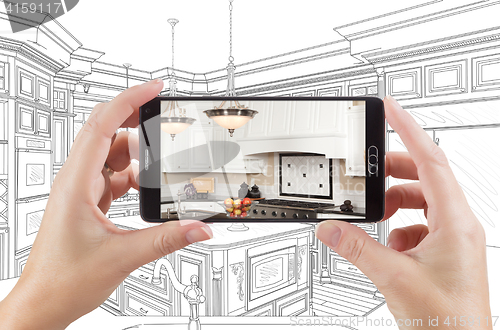 Image of Hands Holding Smart Phone Displaying Photo of Kitchen Drawing Be