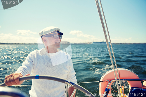 Image of senior man at helm on boat or yacht sailing in sea