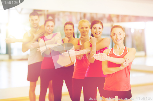 Image of group of smiling people stretching in the gym