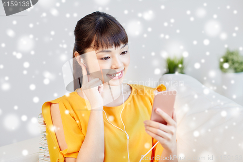 Image of happy asian woman with smartphone and earphones
