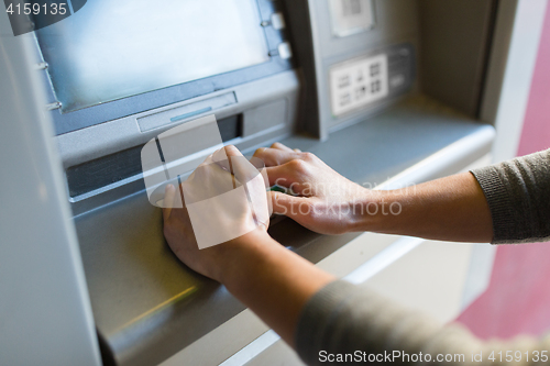 Image of close up of hand entering pin code at atm machine