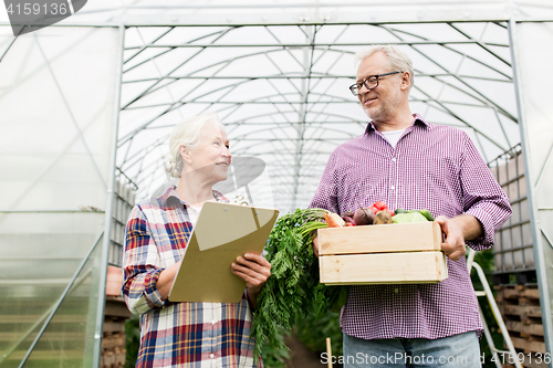 Image of senior couple with box of vegetables on farm