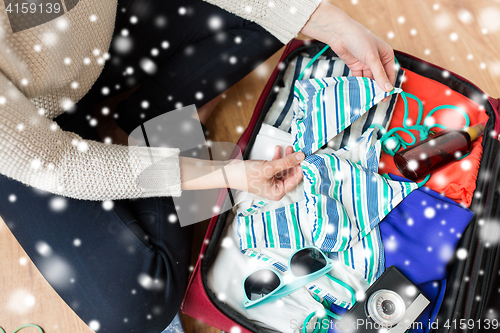 Image of close up of woman packing travel bag for vacation